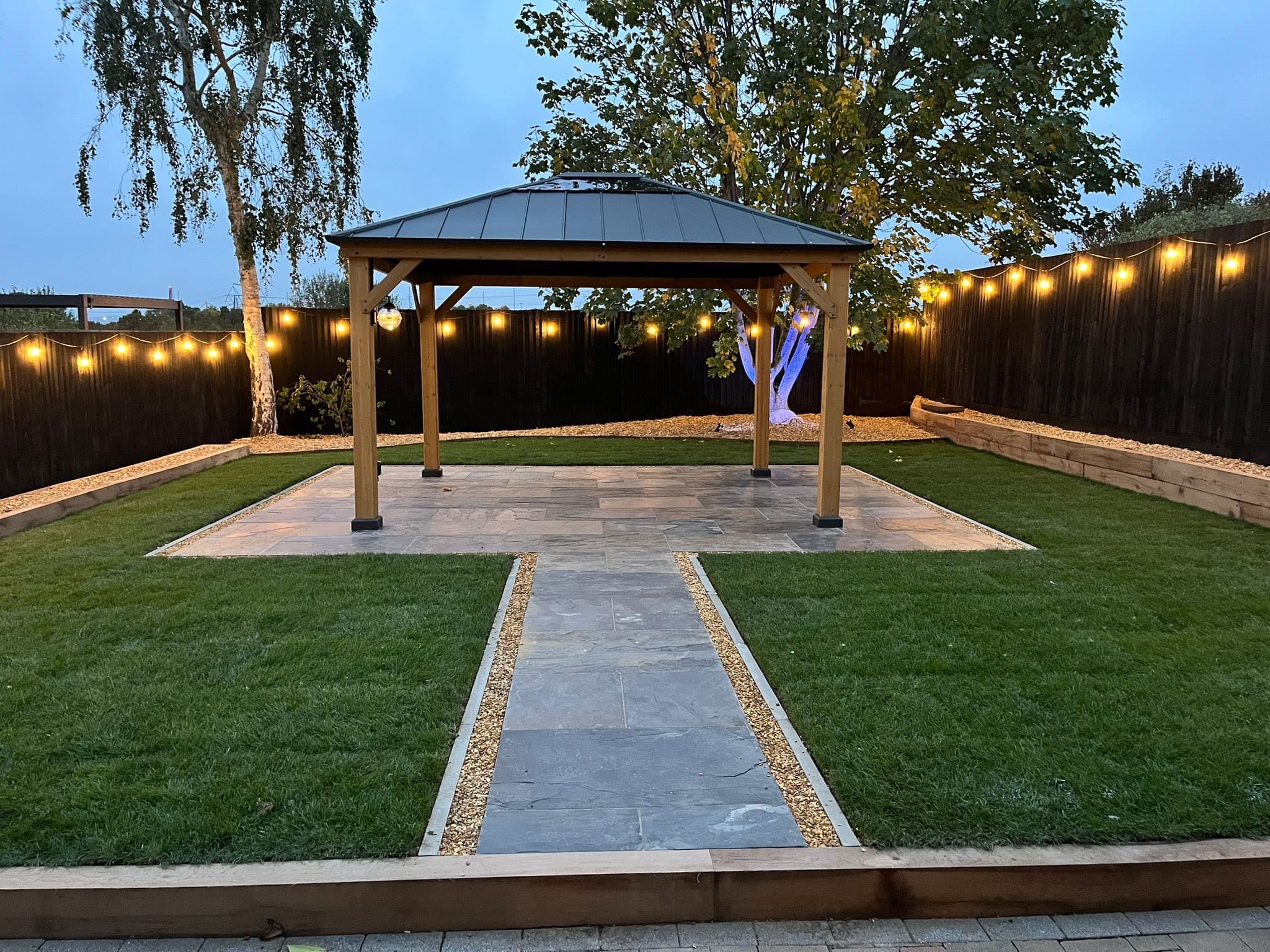 Garden after: stunning gazebo with festoon lights, sandstone path and fresh lawn