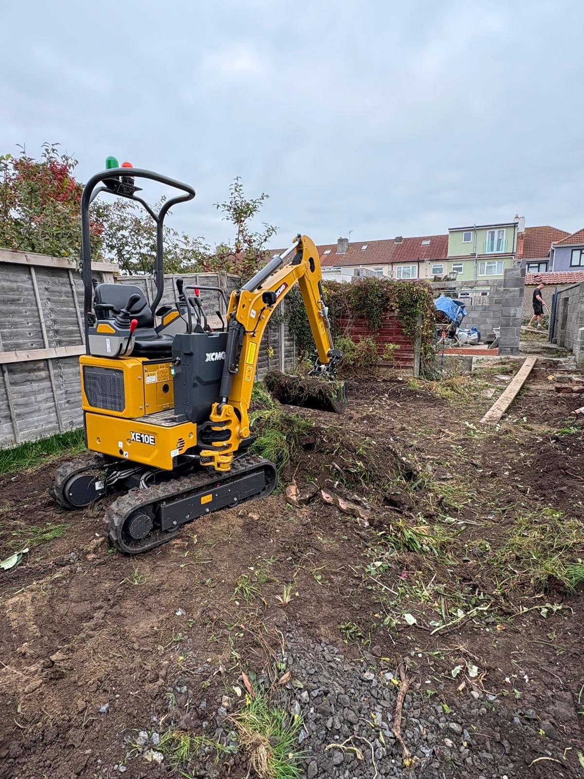 Garden before: overgrown with mini excavator clearing the site